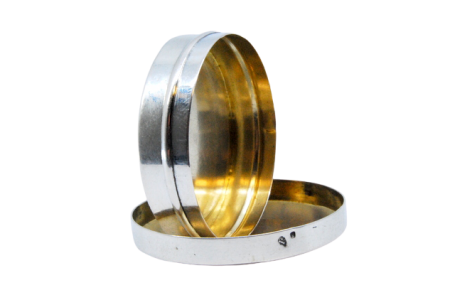 Caixa de comprimidos em prata lisa de forma circular com interior dourado e tampa amovível.
